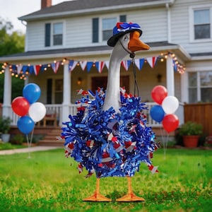 Puede incluir: Una decoración de jardín caprichosa en forma de ganso, adornada con un sombrero patriótico y un collar de oropel azul, blanco y rojo. El ganso se encuentra sobre hierba verde, con globos y una casa al fondo, creando una exhibición festiva al aire libre.