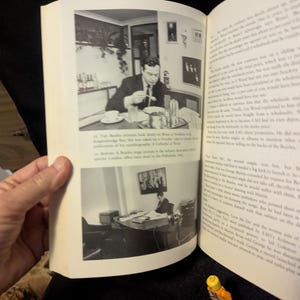Puede incluir: Un libro abierto con fotograf&iacute;as en blanco y negro. Una foto muestra a un hombre comiendo en una mesa, la otra a un hombre en un escritorio. Una peque&ntilde;a figura de Lego est&aacute; en primer plano.