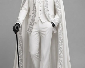 Puede incluir: Un traje blanco que incluye chaleco, pantalón y una capa larga a juego, todo adornado con intrincados bordados plateados en los bordes. El conjunto se completa con una camisa blanca, corbata plateada, guantes negros y un bastón negro.