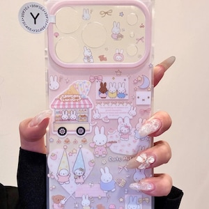 Op de afbeelding: Transparante telefoonhoes met een roze rand met een cartoon konijn ontwerp. De hoes heeft verschillende konijn illustraties, sterren en een zoete cake kar. De tekst "Cute Mif" is zichtbaar op de hoes.