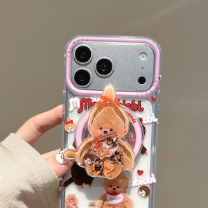 May include: Clear phone case with a pink border and a brown teddy bear design. The case features a clear back with a teddy bear and other small character designs. The camera area is silver with three lenses.