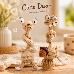 May include: Two handmade crochet figures in tan and white. One figure has large eyes and a red nose, the other holds a brown acorn. The text "Cute Duo" and "Handmade with love" are above the figures.