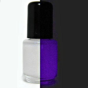 May include: A nail polish bottle with a black lid, split between white glitter polish and purple polish. Text reads "It Glows in the Dark!!" and "Firefly from Hell". A spider and web graphic is in the background.