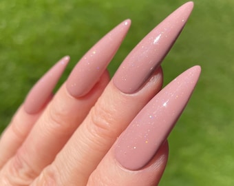 May include: Long, stiletto-shaped artificial nails featuring a smooth, dusty rose pink base color. The surface of each nail is finished with a subtle, fine iridescent glitter that catches the light, creating a soft shimmer across the pointed tips.