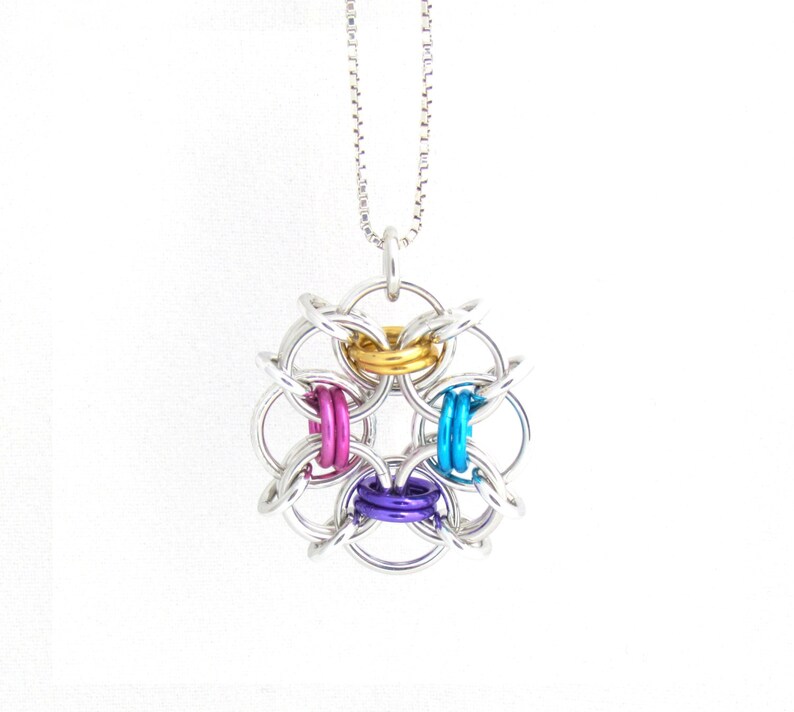 Puede incluir: Un collar de cadena de plata con un colgante de malla de cadena de plata y multicolor. El colgante es de dise&ntilde;o circular con cuatro anillos de malla de cadena de plata y cuatro anillos de malla de cadena de color. Los anillos de color son dorado, rosa, azul y morado.