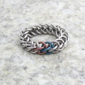 May include: A silver chainmail bracelet with a woven design and three interlocking rings in shades of pink, blue, and green.