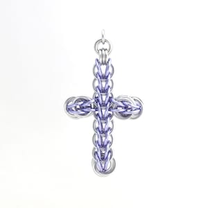 Puede incluir: Un colgante de cruz de metal plateado y morado. La cruz está hecha de anillos entrelazados.