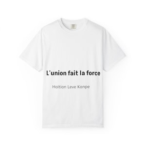 May include: A white t-shirt with the text "L'union fait la force" and "Haitian Leve Kanpe" printed in black. The shirt has a crew neck and short sleeves.