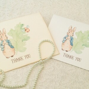 May include: Two thank you cards featuring a watercolor illustration of Peter Rabbit in a blue jacket standing on a green leaf with a bee. The text "Thank You" is printed on each card.