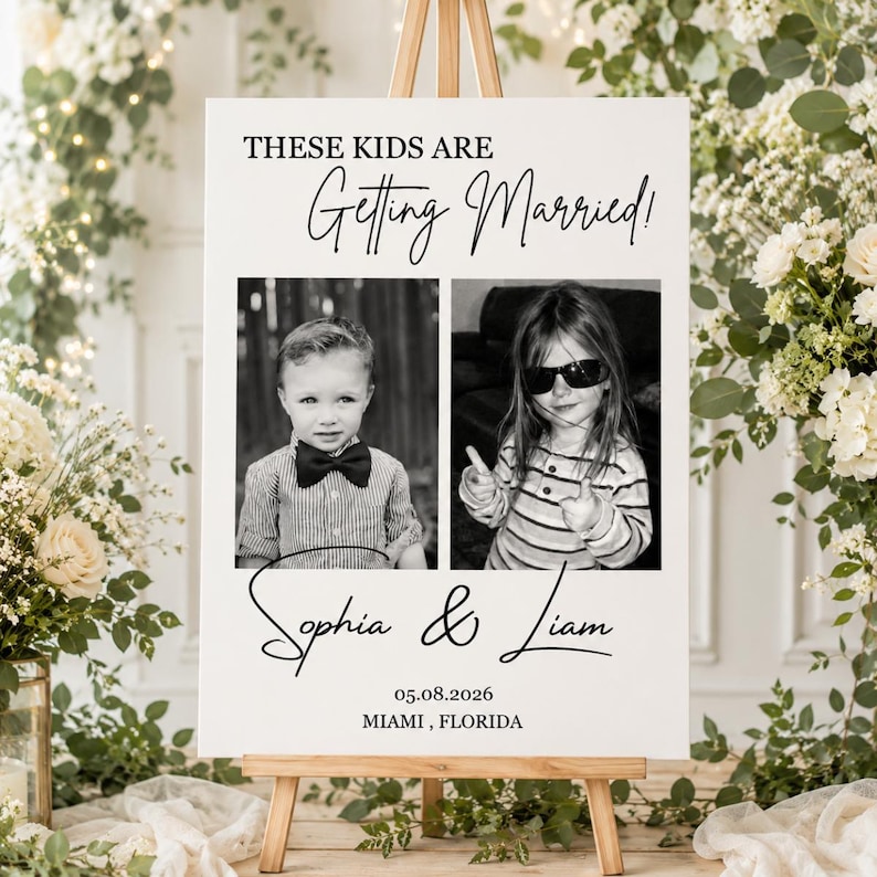 Puede incluir: Un letrero de boda blanco sobre un caballete de madera. El texto "THESE KIDS ARE Getting Married!" est&aacute; escrito en negro. Dos fotos en blanco y negro de ni&ntilde;os est&aacute;n debajo, con los nombres "Sophia & Liam" y la fecha y el lugar.
