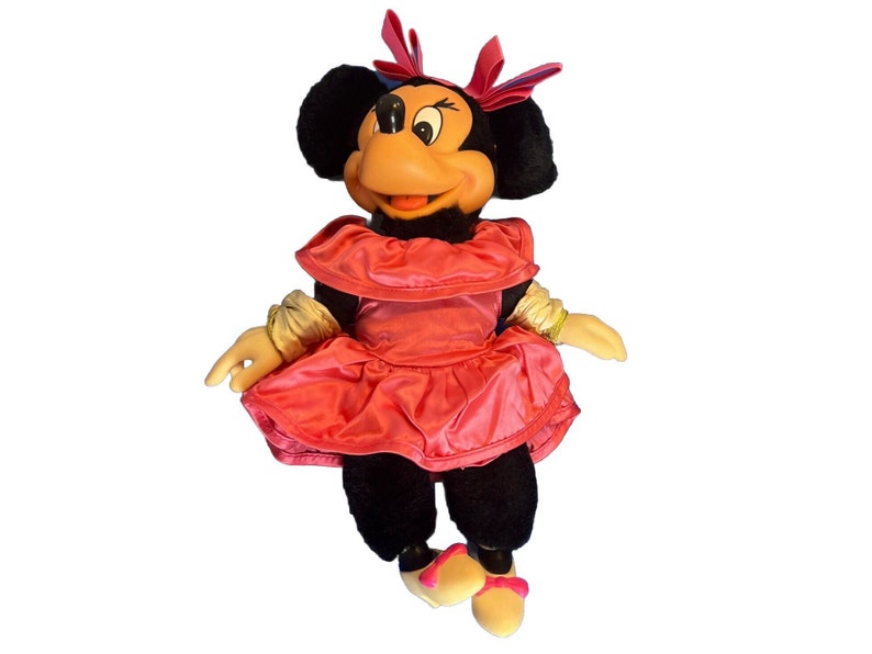 Puede incluir: Mu&ntilde;eca de peluche de Minnie Mouse, con cabeza y cuerpo negros, cara color melocot&oacute;n y vestido rosa brillante. La mu&ntilde;eca tiene un lazo y zapatos rosas a juego, con guantes amarillos. Un personaje cl&aacute;sico de Disney.