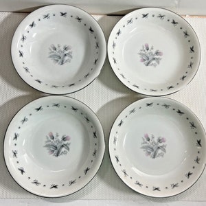 May include: Set of four white ceramic soup bowls with a black and grey floral design. Each bowl has a black rim and a floral design with pink flowers and grey leaves.