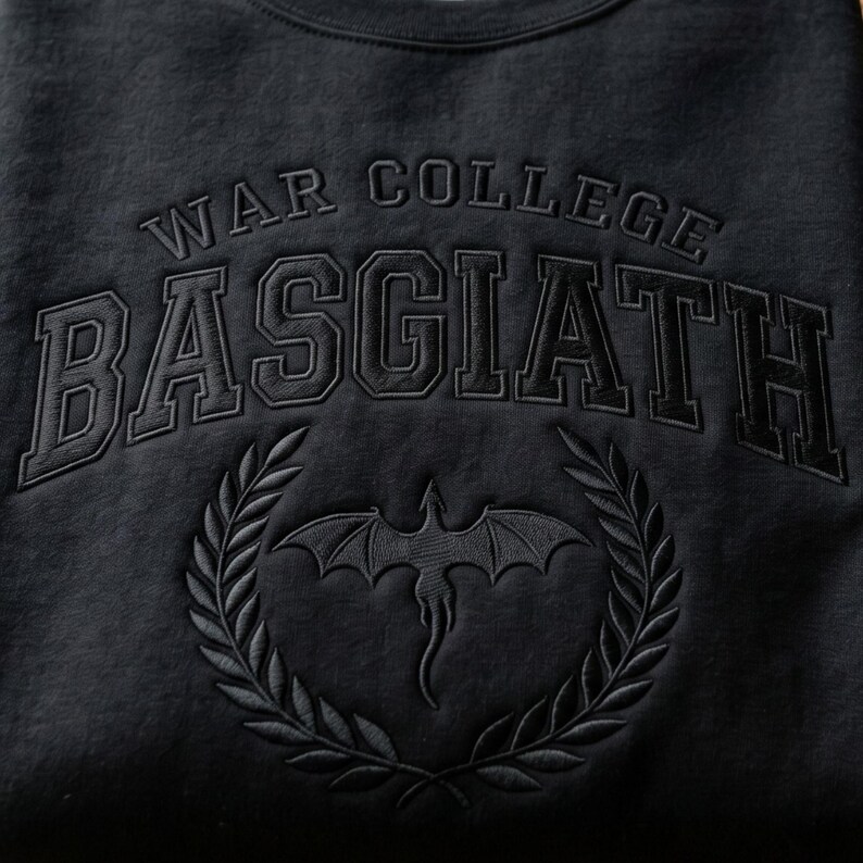 K&ouml;nnte beinhalten: Schwarzes Sweatshirt mit dem Schriftzug "WAR COLLEGE BASGIATH" in einer College-Schriftart. Darunter befindet sich ein Drachenemblem in einem Lorbeerkranz. Das Design ist Ton-in-Ton gestickt.
