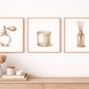 May include: Three framed prints featuring sepia-toned illustrations of a perfume bottle, a candle in a glass, and a reed diffuser. The prints are displayed above a wooden cabinet, with a vase of dried flowers and decorative items.
