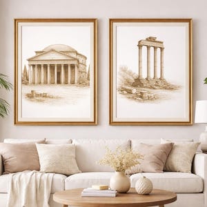 May include: Two framed sepia-toned prints of classical architecture hang above a white sofa. One depicts a domed building with columns, the other, a structure with three columns. The frames are gold, and the room is decorated with plants.