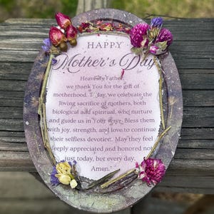 May include: An oval Mother's Day plaque with a floral border. The plaque features the words "HAPPY Mother's Day" and a heartfelt message. Embellished with dried flowers in shades of pink, purple, and yellow, it's a thoughtful gift.
