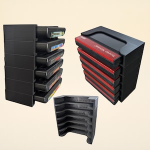 Puede incluir: Tres organizadores de cartuchos de juego negros impresos en 3D. Un organizador contiene seis cartuchos, otro contiene seis cartuchos de juego y un tercer organizador contiene una pila de cartuchos de juego. Los cartuchos son negros con etiquetas coloridas.