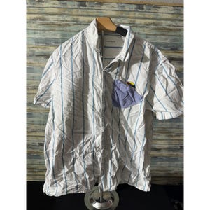 May include: White short-sleeve shirt with vertical blue stripes. The shirt has a light blue pocket with a yellow and red design. The shirt is made of a lightweight fabric and has a button-down front.