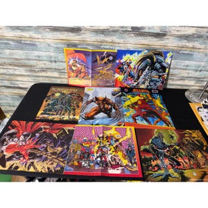 May include: A collection of colorful comic book posters featuring various illustrated characters in action scenes. The posters display dynamic artwork with vibrant colors, including depictions of Wolverine, Batman, and other figures in detailed, multi-panel compositions.
