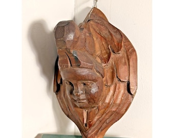 Fragmento arquitectónico religioso antiguo tallado a mano en madera con forma de ángel alado.