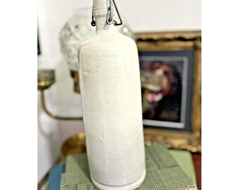 Botella de gres francés vintage con tapa abatible, moteada en gris y beige, estilo rústico.