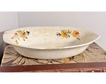 Bol de loza craquelada vintage con estampado floral naranja y amarillo, estilo rústico de granja primitivo.