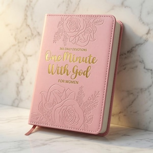 May include: A light pink devotional book with gold foil text that reads 365 DAILY DEVOTIONS One Minute With God FOR WOMEN. The cover features embossed floral designs of roses and leaves, with a matching pink ribbon bookmark extending from the bottom.