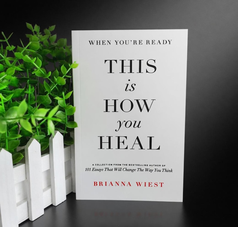 May include: A book titled "This is How You Heal" by Brianna Wiest. The cover is white with black text, including the title and the phrase "When You're Ready." The book is a collection of essays.