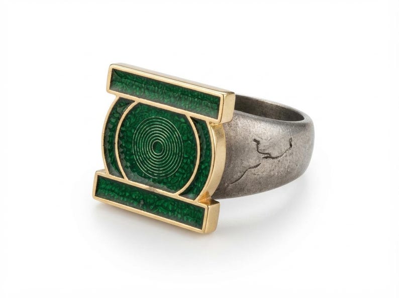 May include: A ring featuring a gold-toned rectangular frame with a central circular motif, both filled with textured green enamel. The band is made of a dark, weathered metallic material with a visible crack-like texture on the outer surface.