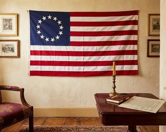 May include: A rectangular Betsy Ross flag featuring thirteen white stars arranged in a circle on a blue canton, with thirteen alternating red and white horizontal stripes. The flag is displayed horizontally against a wall in a room setting.