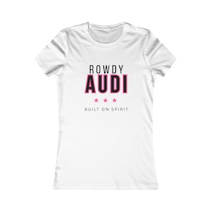 May include: White t-shirt featuring the text "ROWDY AUDI" in black and pink, with three pink stars beneath. The words "BUILT ON SPIRIT" are printed below the stars. The shirt has a crew neck and short sleeves.