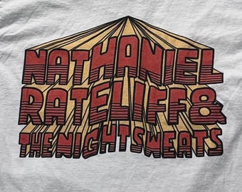 Puede incluir: Una camiseta blanca con un estampado gráfico que muestra el texto NATHANIEL RATELIFF & THE NIGHTSWEATS en una fuente roja tridimensional y audaz con detalles de líneas horizontales, sobre un fondo de diseño de sol radiante color canela.