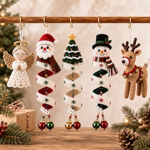 Può includere: Cinque decorazioni natalizie all'uncinetto appese a un'asta di legno. Il set include un angelo con ali dorate, Babbo Natale, un albero di Natale verde, un pupazzo di neve con cappello nero e una renna, tutti con code a spirale e campanellini.