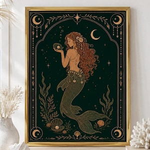 May include: A framed wall art print featuring a mermaid with long wavy hair holding a pearl in a shell. The illustration is set against a dark green background with gold celestial motifs, including crescent moons, stars, and seaweed accents.
