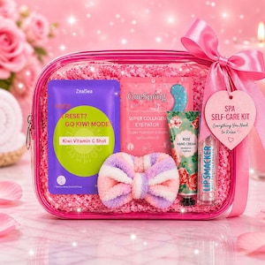 May include: A pink spa self-care kit with a bow, containing a face mask, eye patches, hand cream, and lip balm. The kit includes a purple face mask with the text "RESET? GO KIWI MODE" and a green kiwi graphic. The kit is decorated with pink confetti.