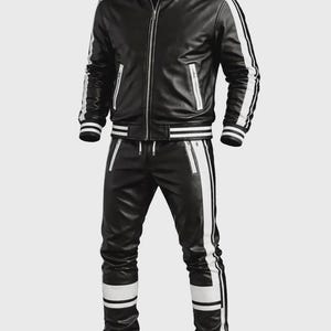以下が含まれることがあります： 白のストライプが入った黒のレザートラックスーツ。ジャケットはジッパー開閉とポケット付き。パンツはドローストリングウエストとサイドにストライプが入っています。「Itzaztraders」のブランド名が上部にあります。