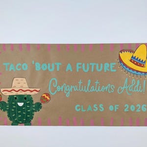 May include: A brown banner with the text "TACO 'BOUT A FUTURE Congratulations Addi! CLASS OF 2026". The banner features a cartoon cactus wearing a sombrero and holding maracas, and a sombrero.
