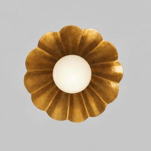 May include: A gold-colored, flower-shaped wall sconce with a white, spherical light bulb in the center. The sconce has a scalloped edge and a metallic finish, creating a decorative lighting fixture.