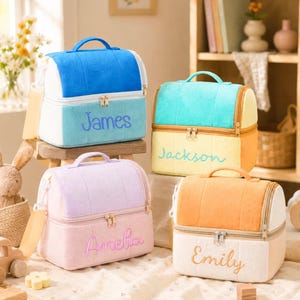 Puede incluir: Cuatro bolsas de almuerzo rectangulares con asas superiores y dos compartimentos con cremallera. Cada bolsa tiene una textura suave similar al fieltro en colores pastel, incluyendo azul, turquesa, lavanda y naranja, con nombres bordados.