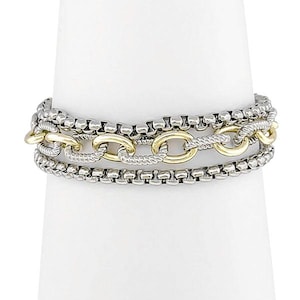 May include: A silver and gold bracelet with three layers of chain links. The top and bottom layers are made of small, round silver links, while the middle layer features gold oval links. The bracelet is displayed on a white stand.