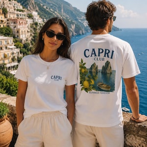 Könnte beinhalten: Zwei weiße T-Shirts mit dem Schriftzug CAPRI CLUB auf der Vorderseite. Die Rückseite des Shirts zeigt eine Grafik mit Zitronen an einem Zweig, einem kleinen Boot auf dem Wasser und dem Text CAPRI CLUB SUMMER FOREVER in dunkelblauer Schrift.