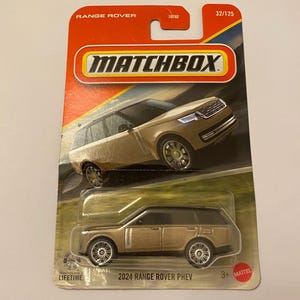 May include: A Matchbox toy car package featuring a gold-colored 2024 Range Rover PHEV. The packaging is red and yellow with the Matchbox logo and the text "Range Rover". The toy car is visible through a clear plastic window.