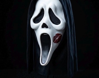 May include: A white ghost-style mask with black eye sockets and a black elongated mouth opening. The mask features a red lipstick kiss mark on the left cheek and is attached to a black fabric hood that drapes down the sides of the face.