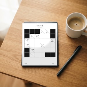 May include: A digital tablet displaying a Kakuro 1 logic puzzle grid with black and white squares, accompanied by a white ceramic mug filled with coffee and a black pen resting on a wooden surface next to the device.