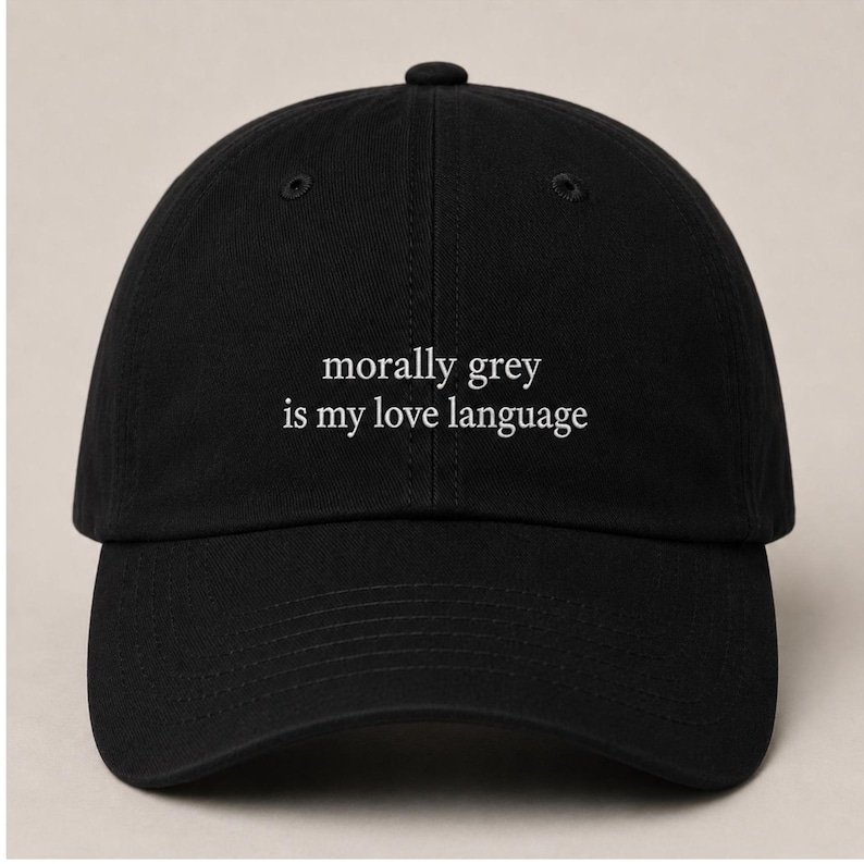 May include: Black baseball cap with the phrase "morally grey is my love language" in white lettering. The cap has a curved brim and a button on top. A casual accessory for everyday wear.