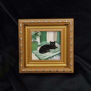 May include: A framed painting of a black cat resting on a green and white striped rug near a window. The painting is in a gold ornate frame. A green potted plant is to the left of the cat.