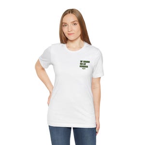 Puede incluir: Camiseta blanca con el texto "IT WORKS ON MY MACHINE" en verde. La camiseta también presenta un símbolo de corchete de código. La camiseta es de estilo cuello redondo y la lleva una persona.