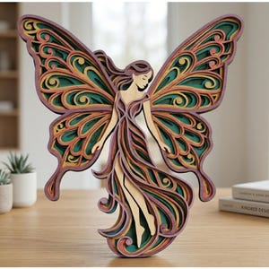 May include: A multi-layered wooden fairy sculpture with butterfly wings. The wings are detailed with green, yellow, and purple hues. The fairy's dress and hair are purple, and the body is natural wood. The sculpture is displayed on a wooden table.