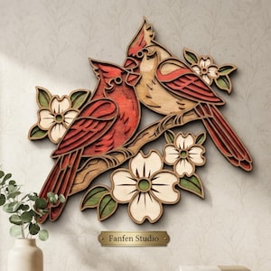 May include: A multi-layered wooden wall art piece featuring two cardinals perched on a branch surrounded by white dogwood flowers with green leaves. The birds are colored in shades of red and tan. A small gold plaque reads Fanfen Studio.