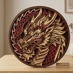 Può includere: Un'opera d'arte da parete circolare in legno a più strati che presenta un design dettagliato di testa di drago in tonalità di legno naturale, marrone scuro e rosso intenso. Gli strati intagliati creano un effetto tridimensionale. Una targhetta riporta Fanfen Studio.